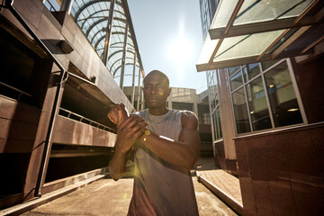 Athlete stretching outdoors under sunlight in a modern urban environment