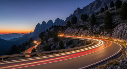 Winding mountain road lit by car trails under a twilight sky