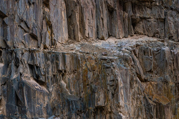 Rugged rock formation in Kyrgyzstan mountains. Textured surfaces reflect the austere beauty of nature under daylight.
