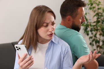 Betrayal. Woman with smartphone talking to her husband at home