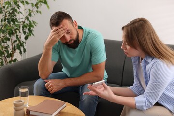Betrayal. Wife showing smartphone with proofs to her unfaithful husband on sofa at home