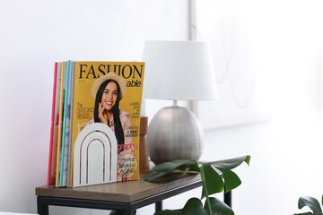 Lifestyle magazines and lamp on wooden table indoors