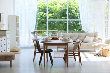 Beautiful table setting, chairs and decor in dining room. Interior design