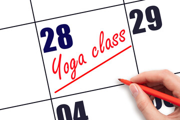 28th day of the month.  Hand writing Yoga class reminder and drawing a line on calendar with red...