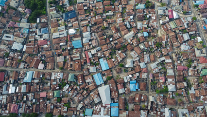 Aerial view of a densely packed settlement with various rooftops and narrow pathways during daytime