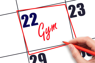 22nd day of the month. Hand writing Gym reminder and drawing red frame on calendar with red pen on...