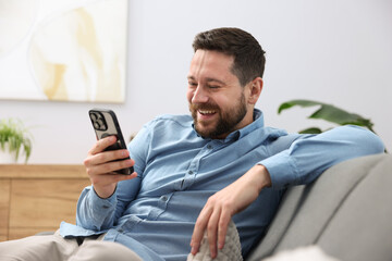 Man laughing while watching something on smartphone at home