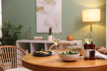 Dinner table with tasty food and white wine in stylish room