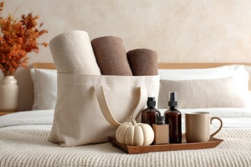 Spa essentials on bed with towels, bottles, and cozy decor in warm tones. Guestroom essentials like towels, small gifts, and toiletries in a tote bag on a bed with fall decor