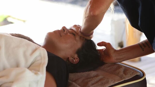 Masseuse performing craniosacral therapy on client's forehead