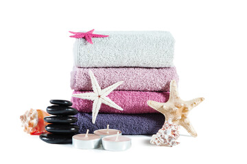 Stack of multicolored towels, candles, pebbles, shells and starfish.