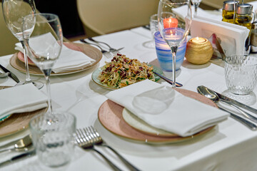 An Elegant Dining Table Setting with Gourmet Salad, Sparkling Glassware, and Soft Candlelight for an Inviting Culinary Experience
