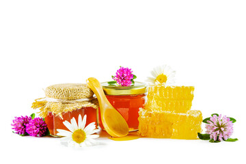 Jar with honey, honeycomb, clover and chamomile flowers and wooden spoon for honey.