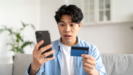 A stunned individual looking at a phone screen and holding a credit card, expressing financial concern or shock. A person seems concerned about unexpected expenses and potential debt.