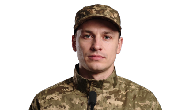 Portrait of a soldier in camouflage uniform, displaying determination and resolve. The man is wearing a cap and looking straight ahead.