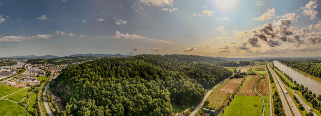 Blick auf eine malerische Landschaft mit Hügeln, Fluss und Stadt in der Vormittagssonne.