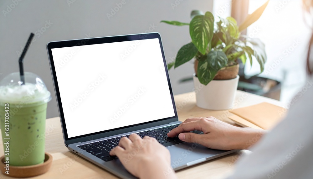 Aufkleber person using a laptop computer at a modern workspace with beverage and plant. the person is typing o