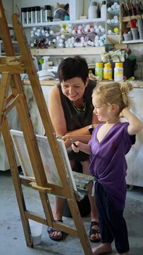 Child painting with an grandmother in a cozy art studio. Candid indoor moment of creativity and learning. Artistic lifestyle scene with real people and natural light.