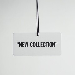 Minimal New Collection Label. Description: White card with black text “NEW COLLECTION” hanging from a string—clean promo concept.