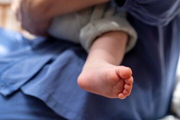 Baby's foot hanging down while being held, showcasing tenderness and love in a cozy setting
