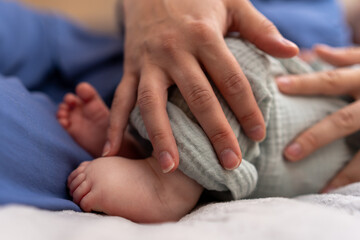 Mother's hands hold gently the tiny feet of a baby. concept of care, protection and love. family...