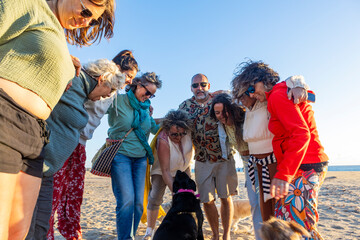 Group of people hugging with their dogs on the beach at sunset after a spiritual retreat