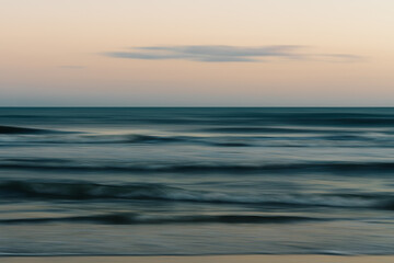 Serene waves gently roll toward the shore at sunset.