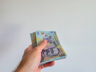 Romanian lei bank notes held in hand against a white background