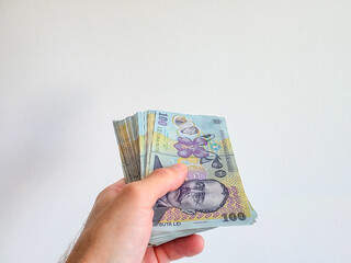 Romanian lei bank notes held in hand against a white background