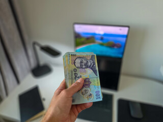 Romanian lei bank notes held in hand against a desk background