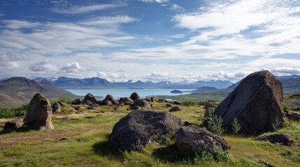 A stunning landscape featuring large rocks, lush greenery, and a serene lake, set against a backdrop of mountains and a partly cloudy sky.