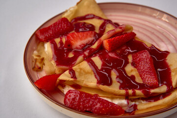 Deliciously Homemade Crepes with Fresh Strawberries and Berry Syrup for a Delightful Dessert Experience