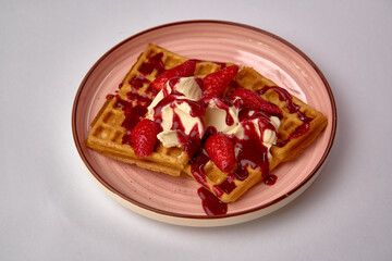 Indulgent Waffles Topped with Creamy Ice Cream, Fresh Strawberries, and Drizzled with Rich Strawberry Sauce in a Beautifully Curved Plate