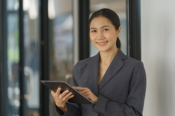 Smiling female office worker checking reports and using a digital tablet at the office.
