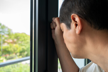 Side view portrait of a sad single man and mad sitting by the window in regret