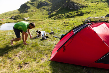 Fototapeta premium camping with dog and red tent in high mountains