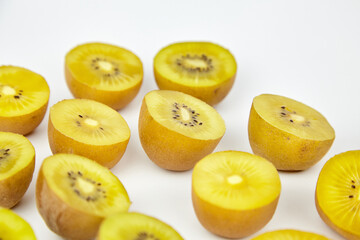 Fresh yellow kiwifruit halves arranged on a white background, showcasing vibrant color and texture, ideal for healthy eating concepts and culinary presentations