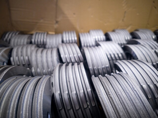 Steel components stacked neatly in a cardboard box at an industrial workshop in the morning light