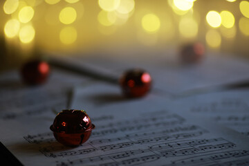 Festive Bells on Sheet Music with Warm Bokeh Lights in Background for Holiday Season