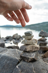 A woman hand building a cairns by the lake in Norway
