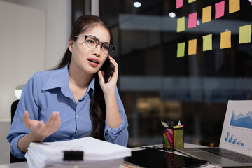 Businesswoman feeling stressed working at desk in office night time.