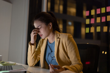 Businesswoman feeling stressed working at desk in office night time.