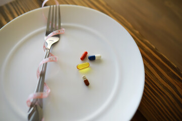 Diet and Medication Concept with Pills on Plate and Fork Wrapped in Measuring Tape