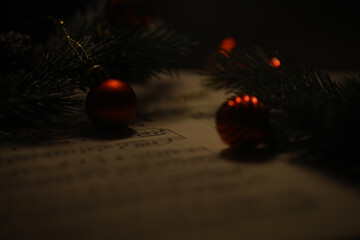 Close-Up of Christmas Ornaments and Pine Branches on a Musical Sheet in Warm Light