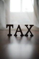 Bold Wooden 'TAX' Letters on a Wooden Floor With Bright Background