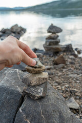 A woman hand building a cairns by the lake in Norway