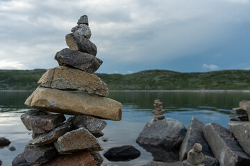 Stone cairns in the wind in Norway near a lake.