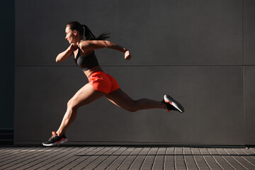 Woman in sportswear running near building outdoors
