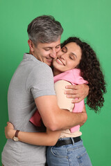 Happy friends hugging each other on green background