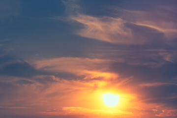 Golden light spills through layered clouds as the sun sets, creating a dramatic contrast of shadow and warmth. Sky texture shifts from soft pastels to deep grays, evoking a sense of calm and awe